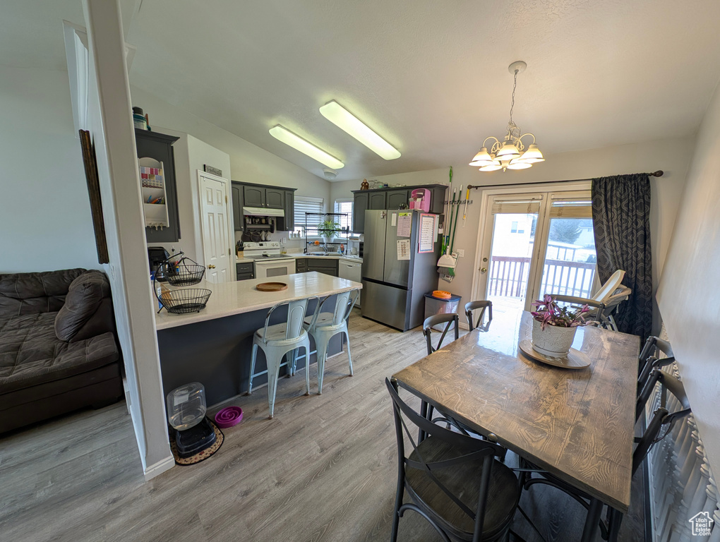Dining room featuring lofted ceiling, light wood-type flooring, and a notable chandelier