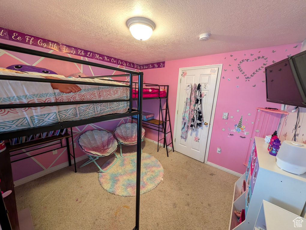 Carpeted bedroom featuring baseboards and a textured ceiling