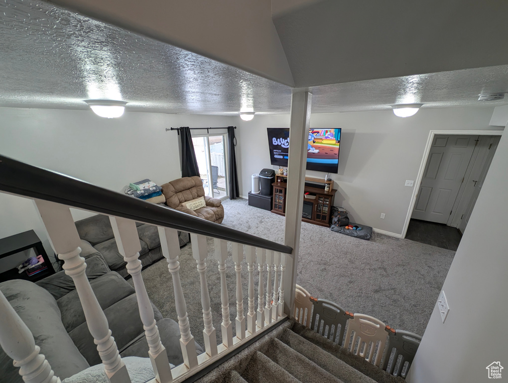 Stairs with carpet flooring, a textured ceiling, and baseboards