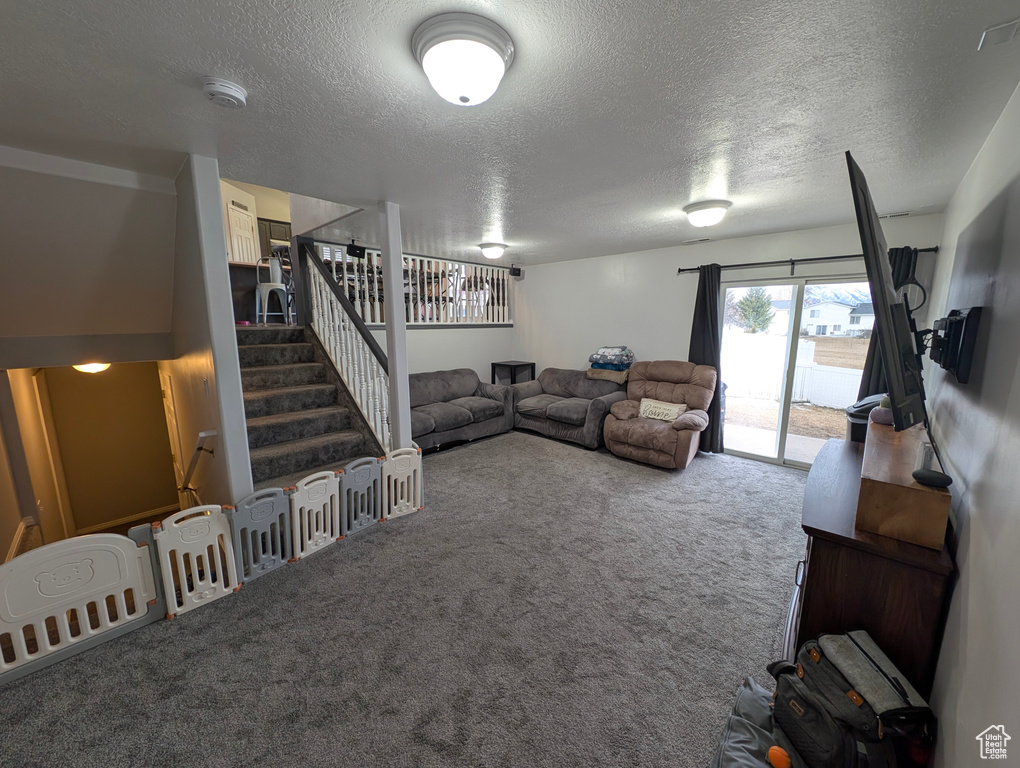 Carpeted living room with a textured ceiling and stairway