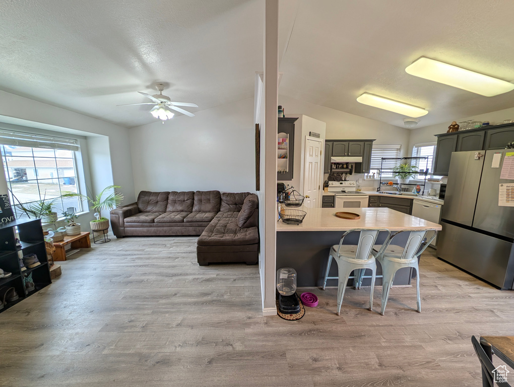 Kitchen with lofted ceiling, white appliances, light countertops, and a kitchen bar