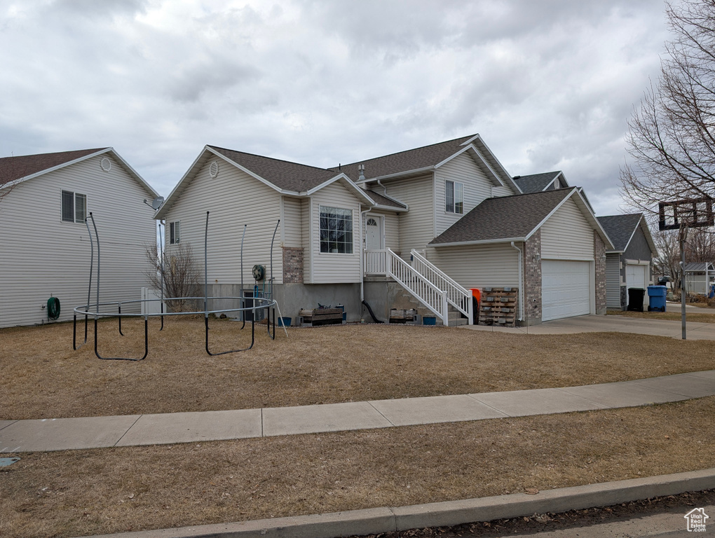 View of front facade featuring concrete driveway, a playground, and an attached garage