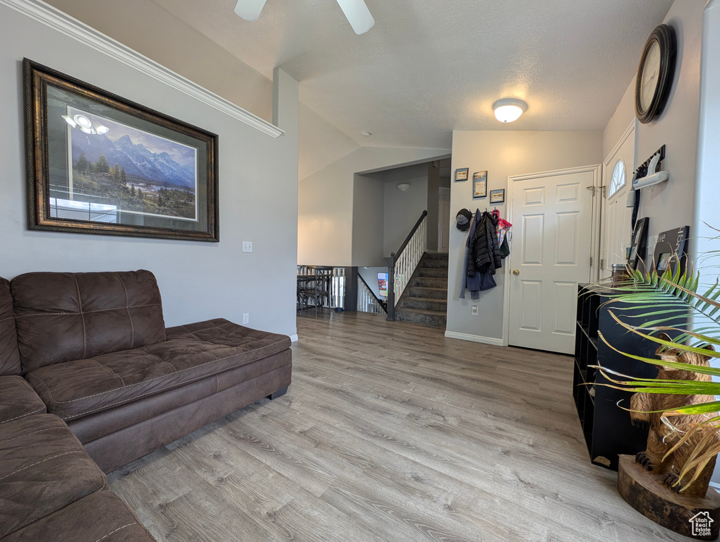 Living area featuring vaulted ceiling, stairway, and light wood-type flooring
