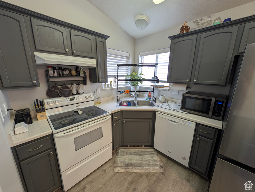Kitchen featuring vaulted ceiling, stainless steel appliances, a sink, and light countertops