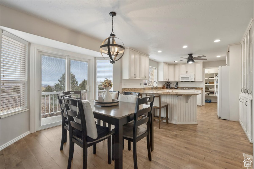 Dining area with recessed lighting, baseboards, light wood finished floors, and ceiling fan with notable chandelier