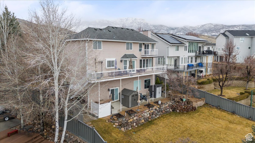 Back of house featuring a fenced backyard, a mountain view, a lawn, a residential view, and a chimney