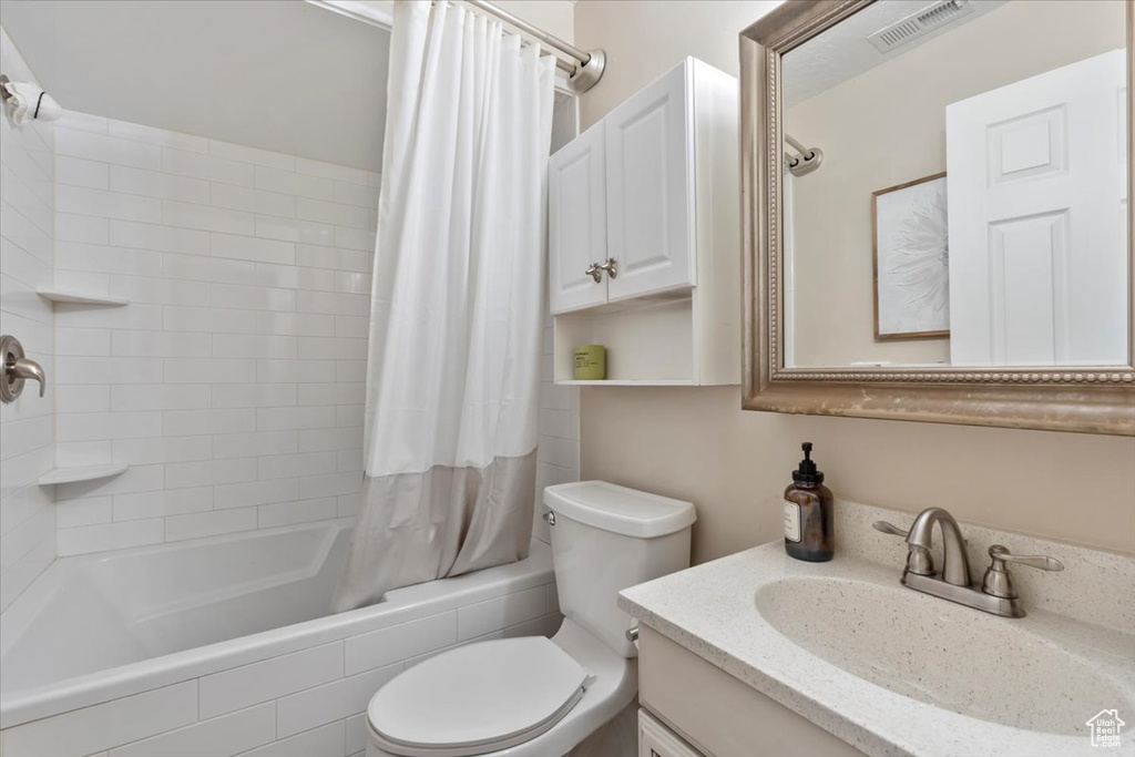 Bathroom featuring toilet, shower / bath combo, vanity, and visible vents