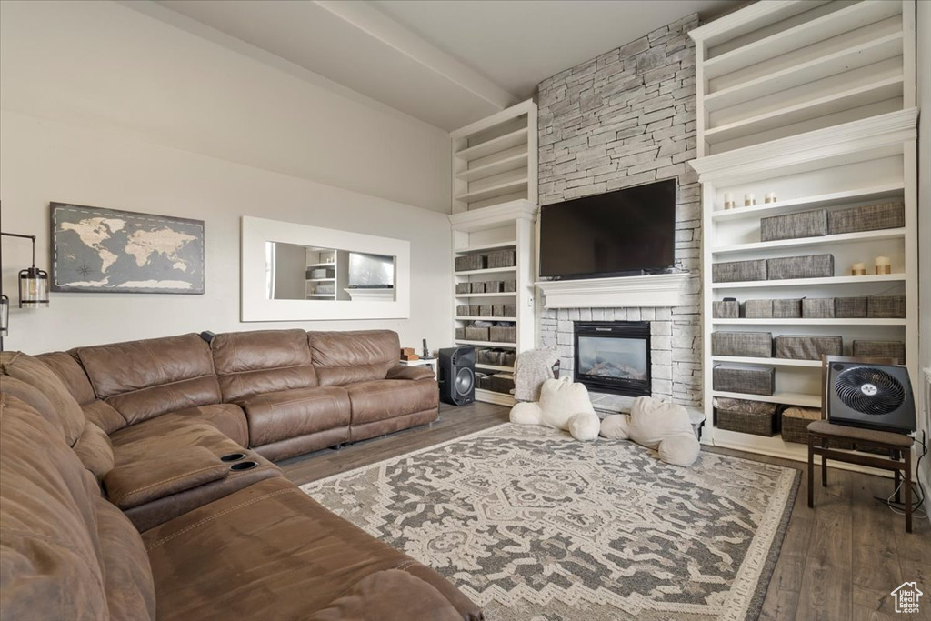 Living area featuring a towering ceiling, built in features, wood finished floors, and a stone fireplace