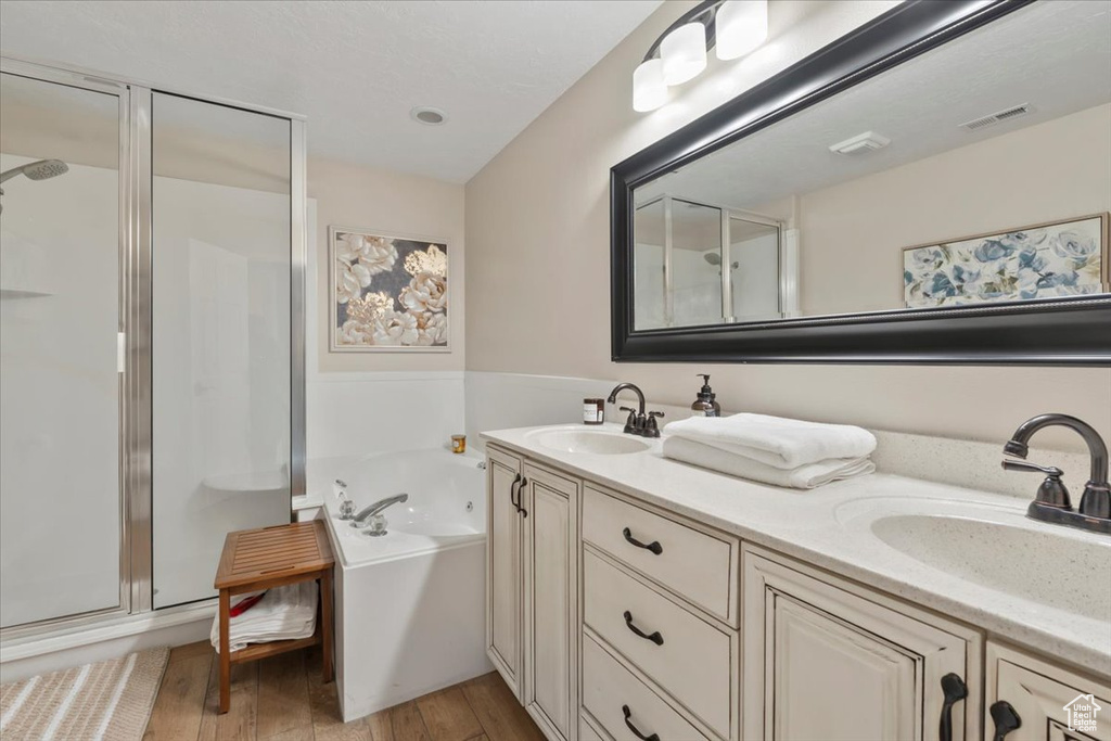 Bathroom with wood finished floors, a stall shower, and a sink