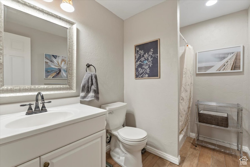 Full bath featuring a shower with curtain, vanity, toilet, and wood finished floors