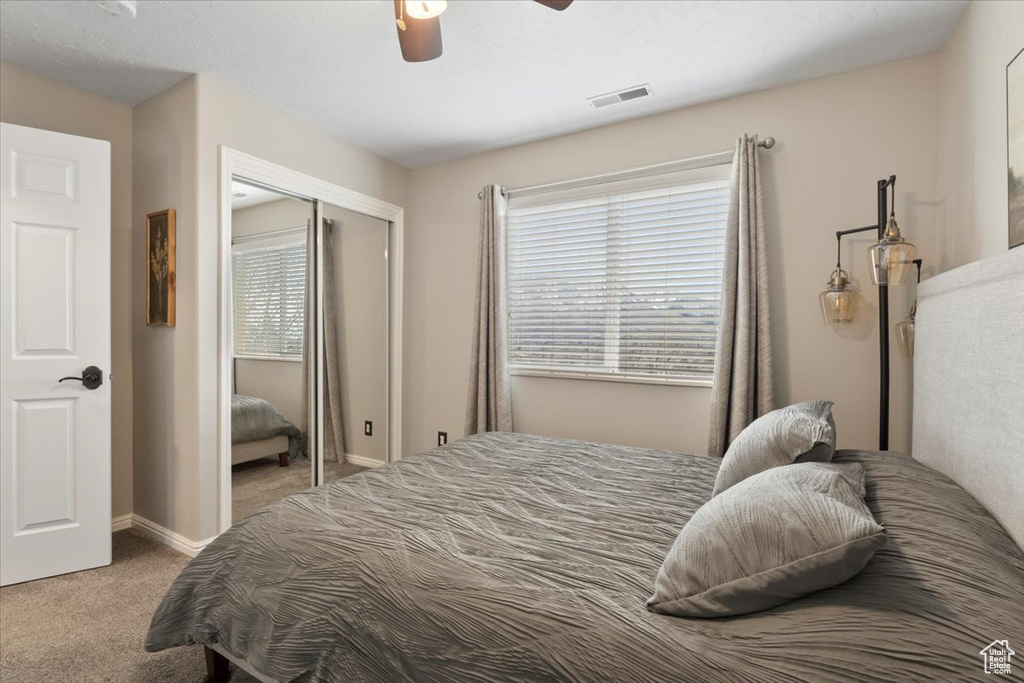 Bedroom with baseboards, visible vents, ceiling fan, carpet flooring, and a closet