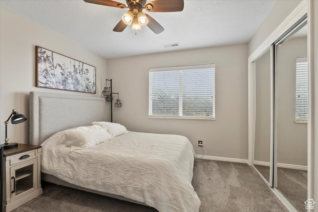 Bedroom featuring a ceiling fan, visible vents, baseboards, a closet, and dark carpet