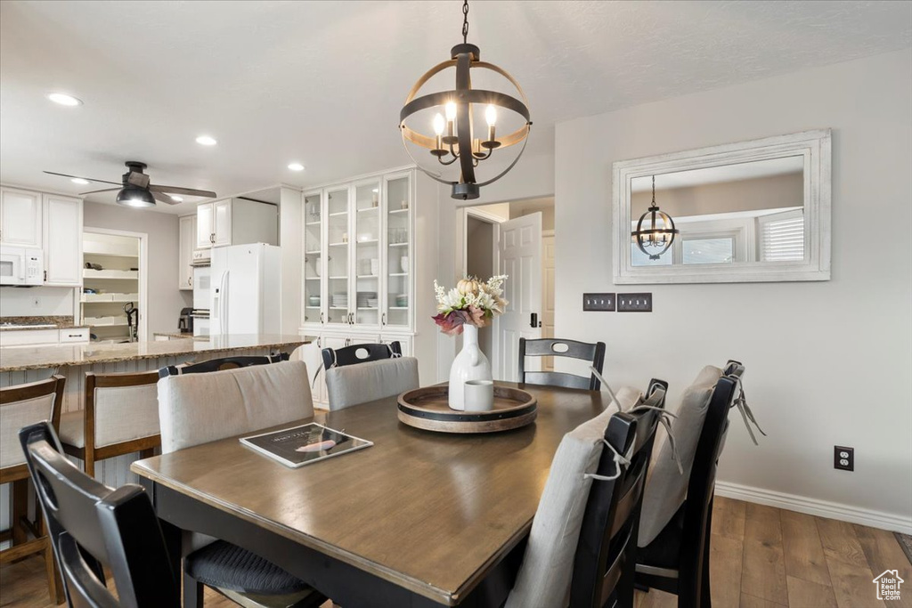 Dining room featuring baseboards, ceiling fan with notable chandelier, dark wood-type flooring, and recessed lighting