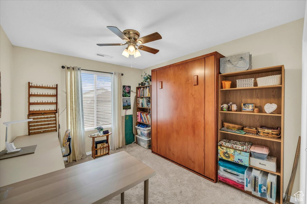Home office with a ceiling fan, light colored carpet, and visible vents