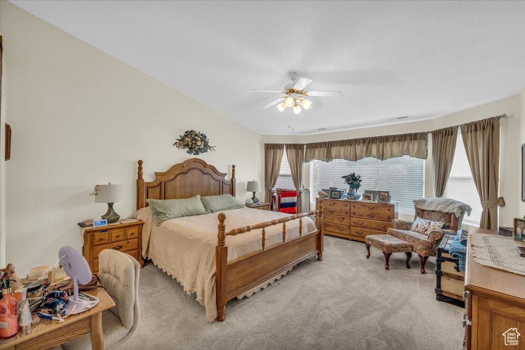 Bedroom with ceiling fan, multiple windows, and light colored carpet