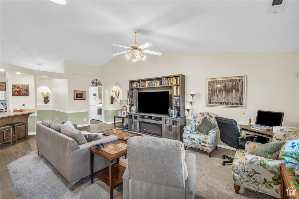 Living area with lofted ceiling, wood finished floors, visible vents, a ceiling fan, and baseboards