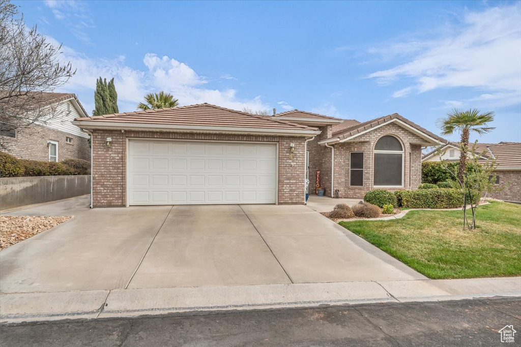 Ranch-style house with a garage, driveway, a front lawn, and brick siding