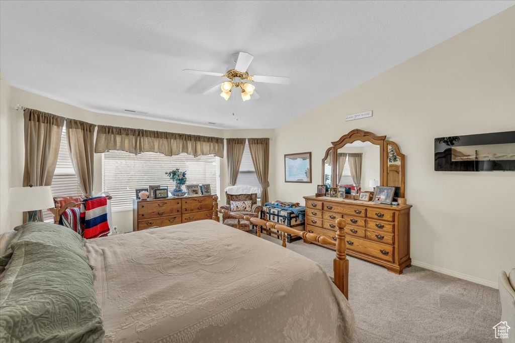 Carpeted bedroom with lofted ceiling, ceiling fan, and baseboards