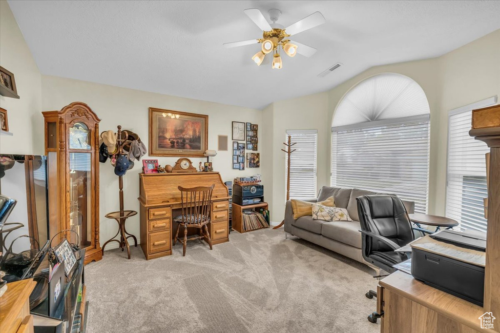 Office space with ceiling fan, vaulted ceiling, a wealth of natural light, and light colored carpet