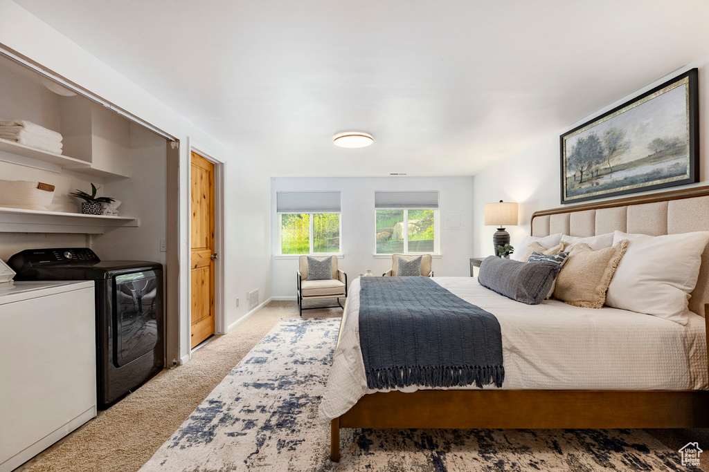 Carpeted bedroom with washer and clothes dryer