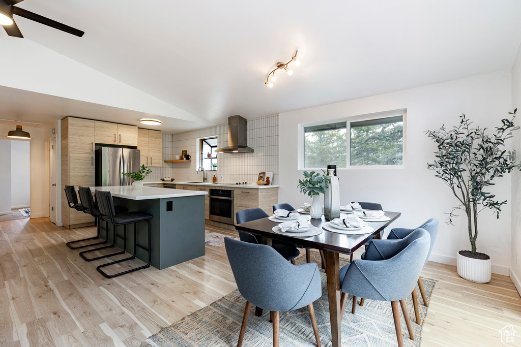 Dining space featuring light wood-type flooring, lofted ceiling, a ceiling fan, and baseboards