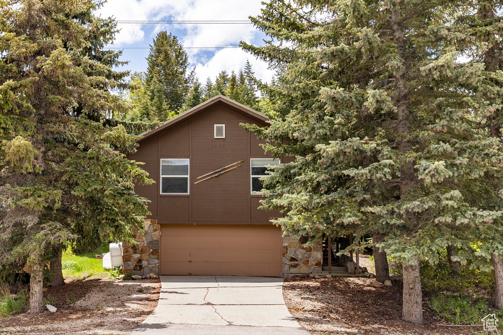 View of front facade featuring concrete driveway, a garage, and stone siding