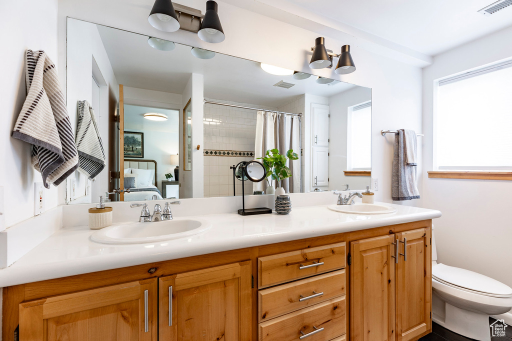 Full bath with double vanity, toilet, and a shower with curtain