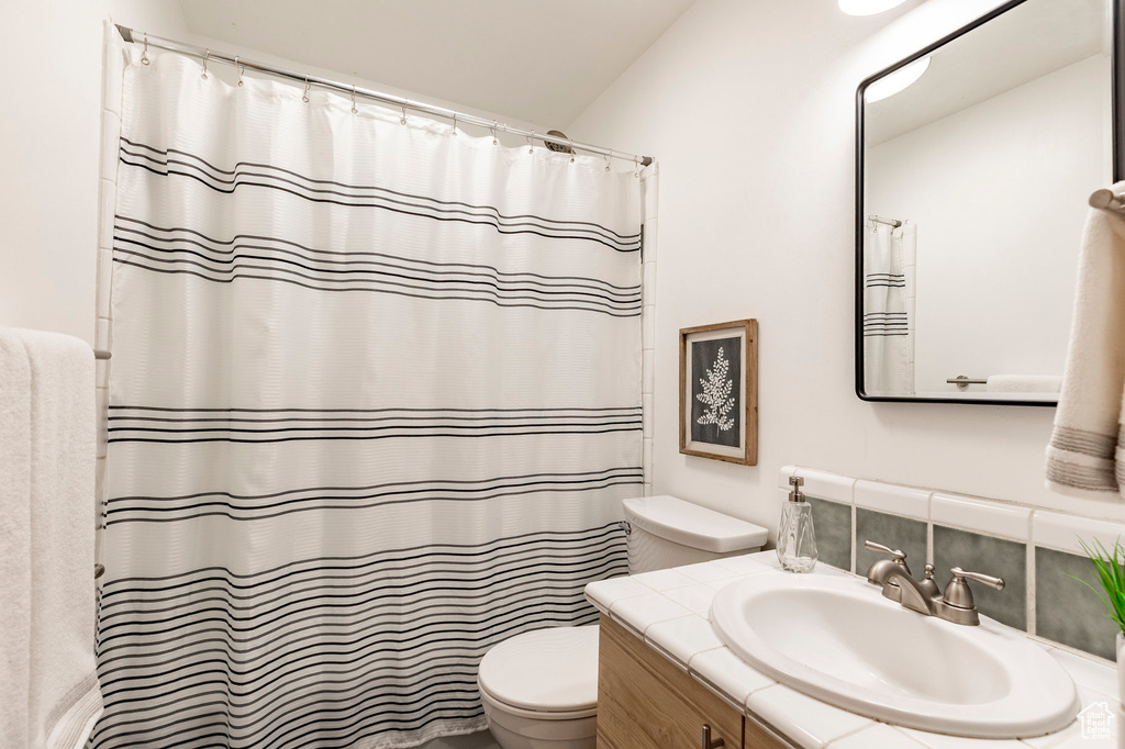 Bathroom featuring toilet, vanity, and a shower with curtain