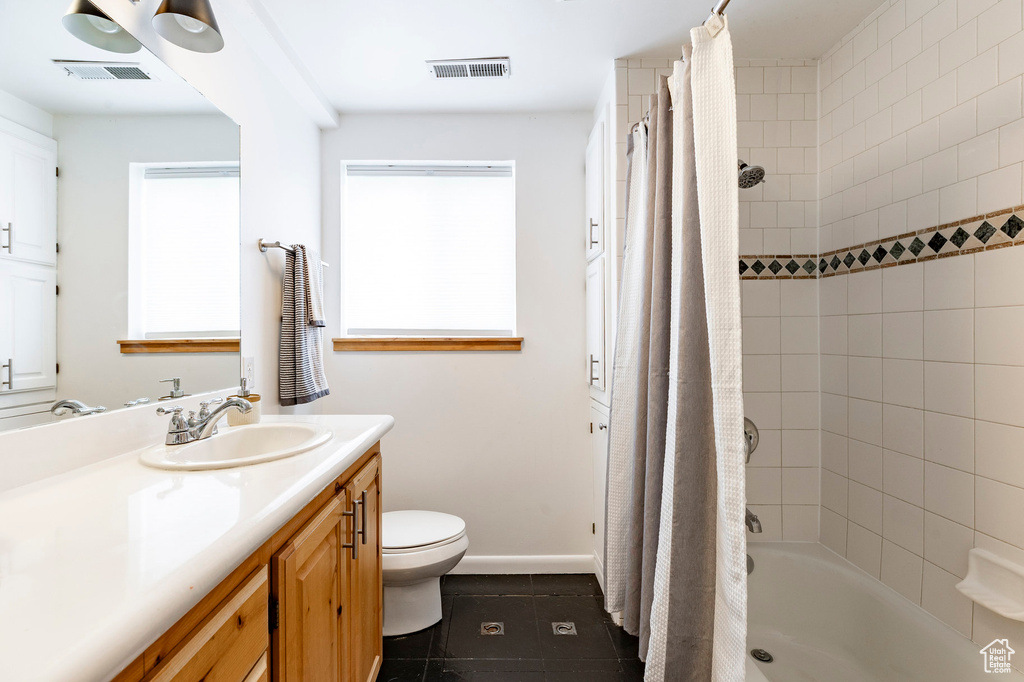 Full bathroom with tile patterned flooring, vanity, toilet, shower / tub combo with curtain, and baseboards