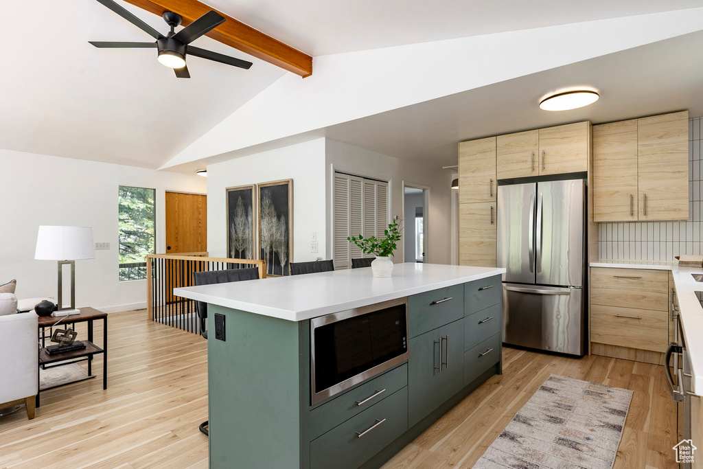 Kitchen with appliances with stainless steel finishes, a ceiling fan, a kitchen island, and light countertops
