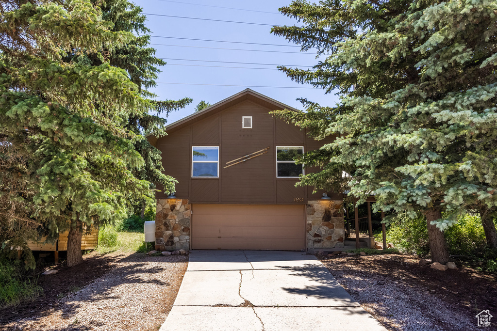 View of front of home featuring concrete driveway, an attached garage, and stone siding