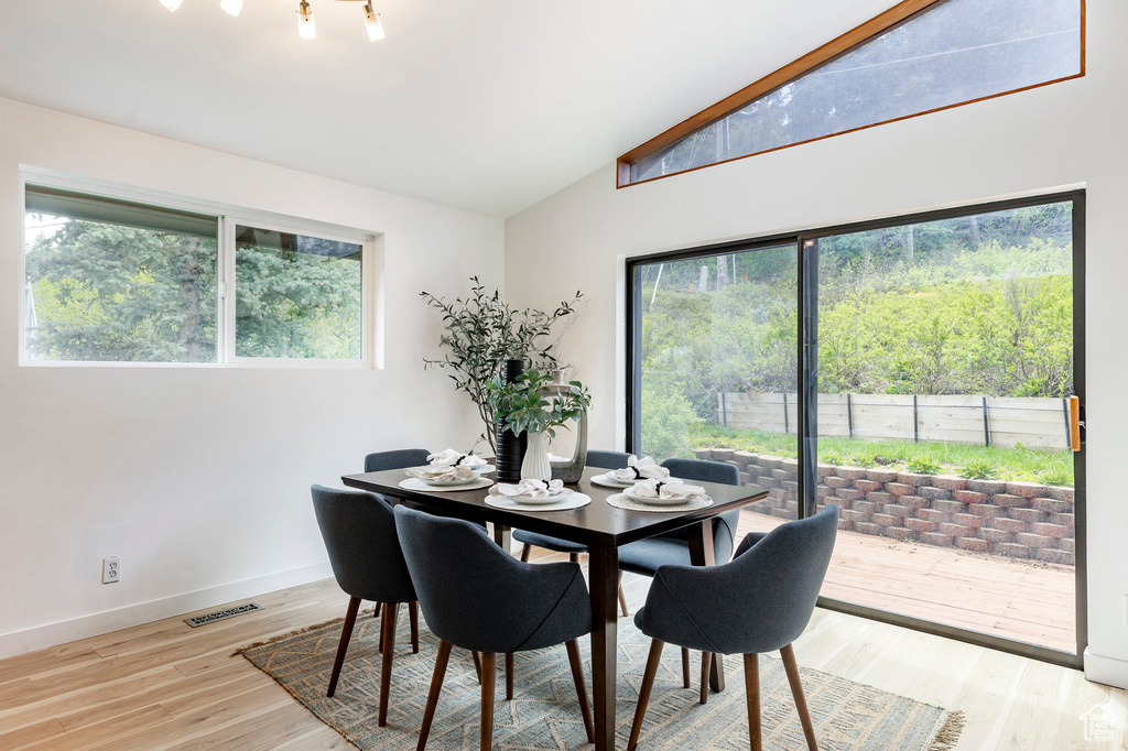 Dining area with vaulted ceiling, light wood finished floors, and baseboards