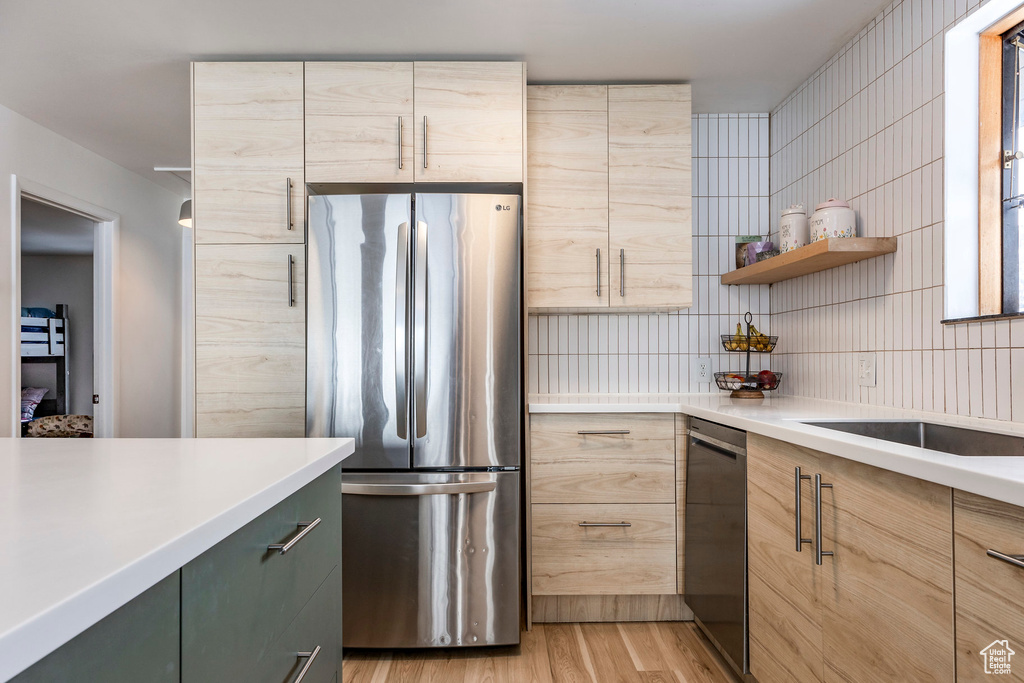 Kitchen with appliances with stainless steel finishes, light brown cabinets, light wood-type flooring, open shelves, and light countertops