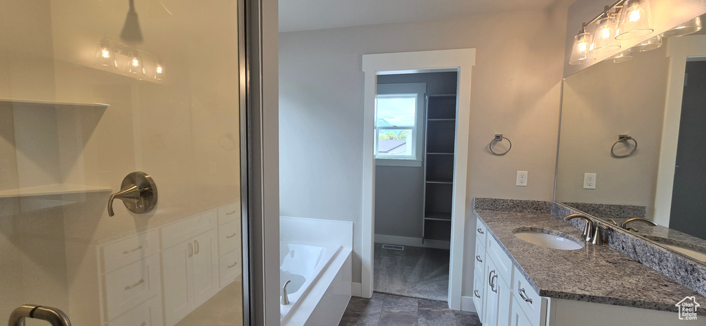 Bathroom with a shower stall, baseboards, a garden tub, and vanity