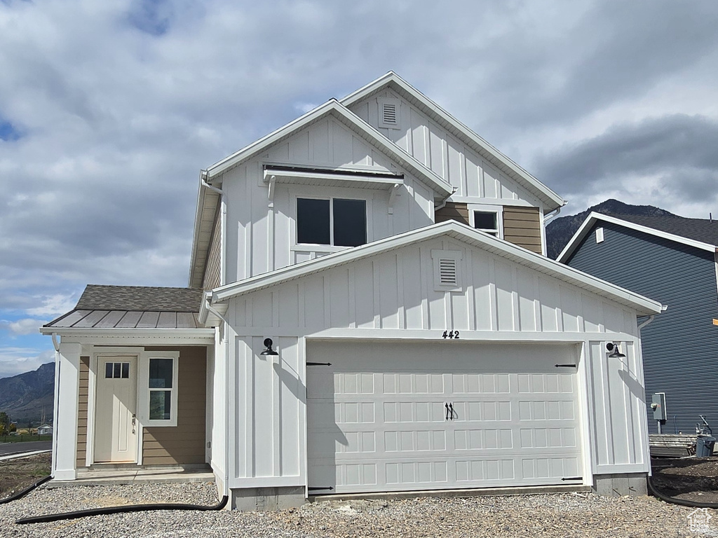 View of front of home featuring driveway, an attached garage, a mountain view, and board and batten siding