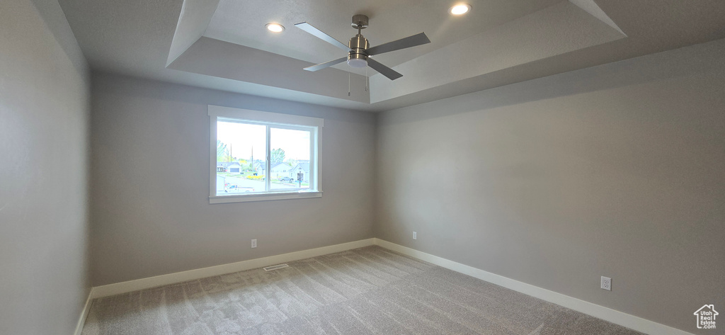 Empty room featuring recessed lighting, baseboards, ceiling fan, a raised ceiling, and light colored carpet