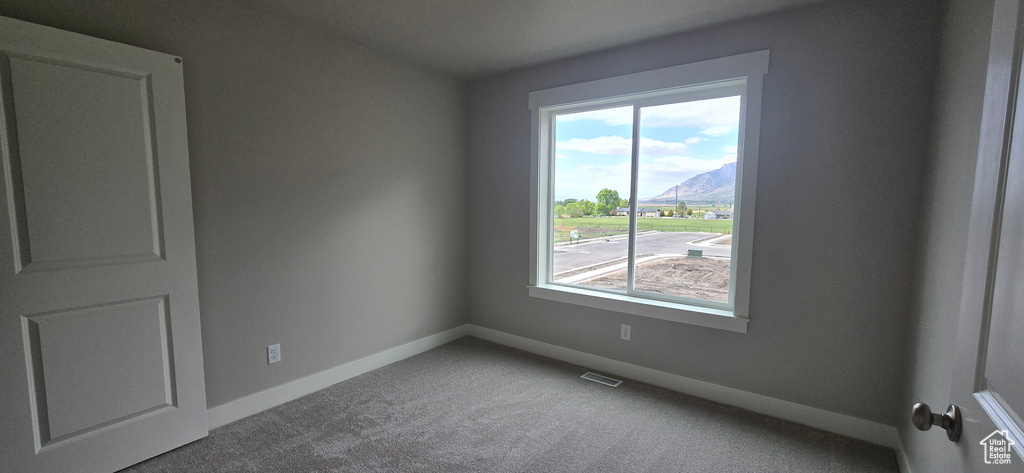 Empty room featuring a mountain view, a wealth of natural light, baseboards, and visible vents