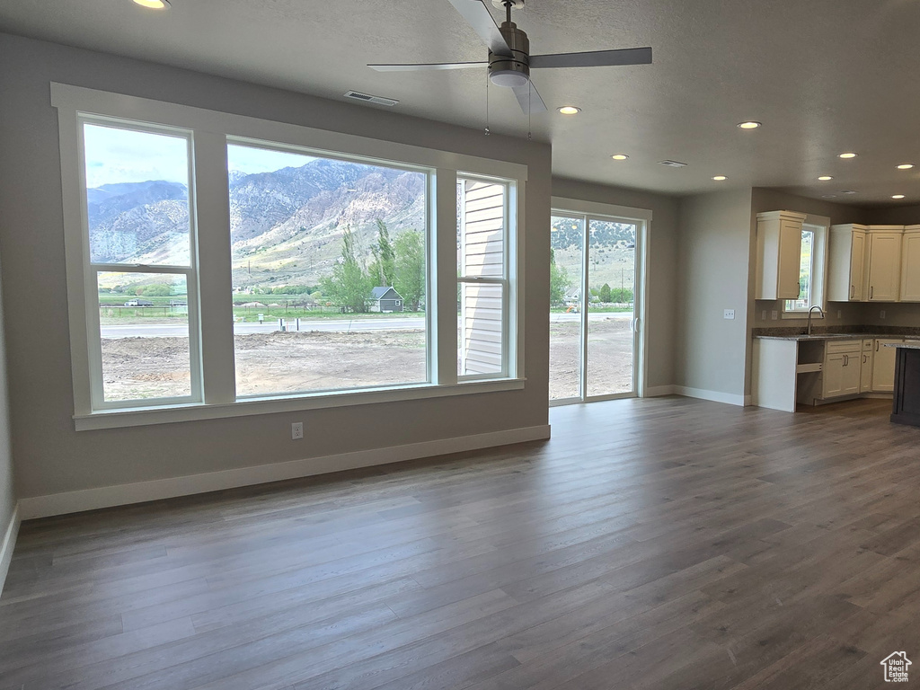 Unfurnished living room with ceiling fan, visible vents, baseboards, and a healthy amount of sunlight