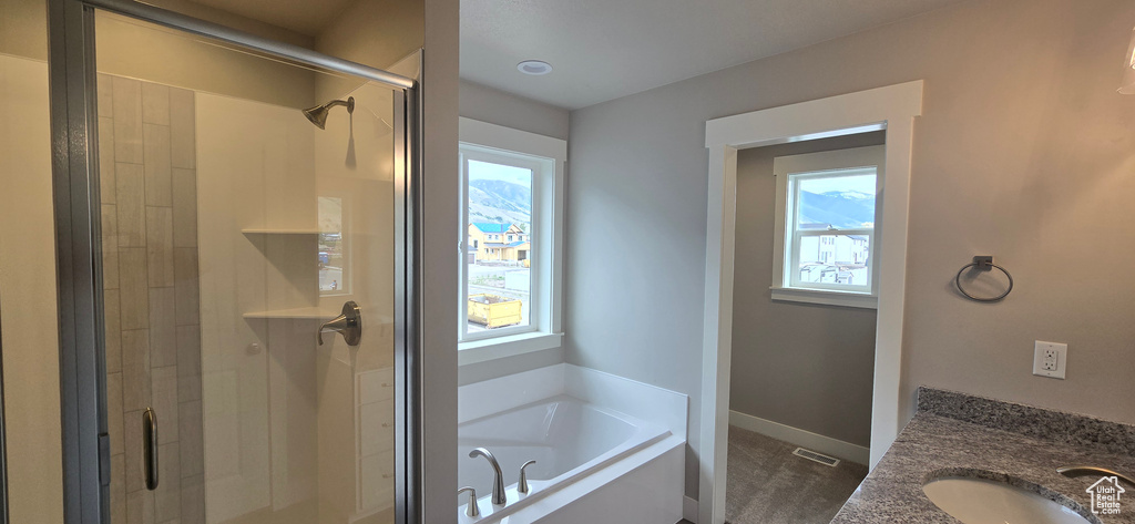 Full bathroom with a stall shower, a bath, baseboards, and a sink