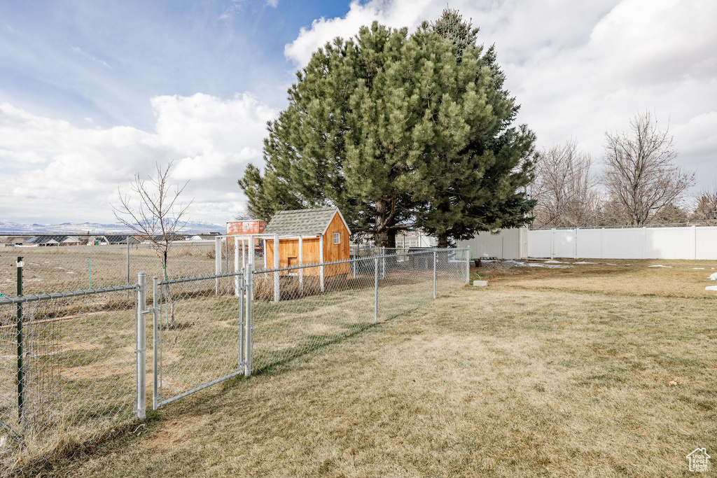 View of yard featuring a fenced backyard, a rural view, a gate, a storage unit, and an outdoor structure