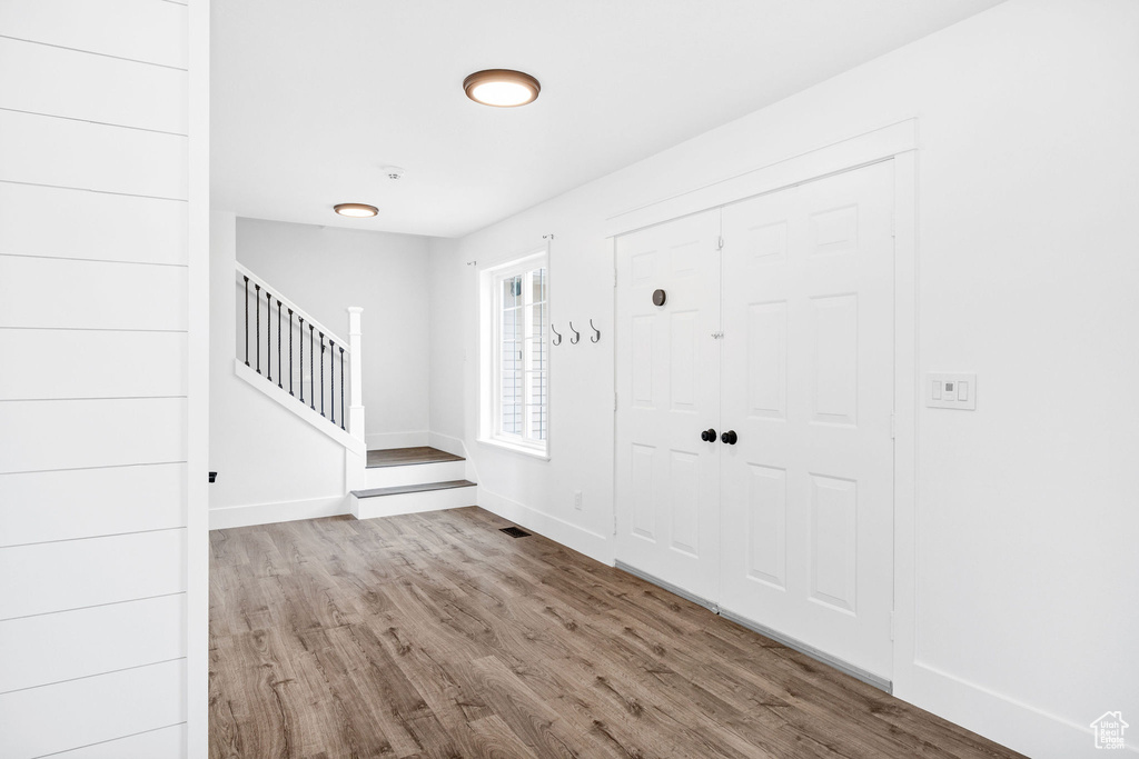 Foyer entrance featuring stairs, wood finished floors, visible vents, and baseboards
