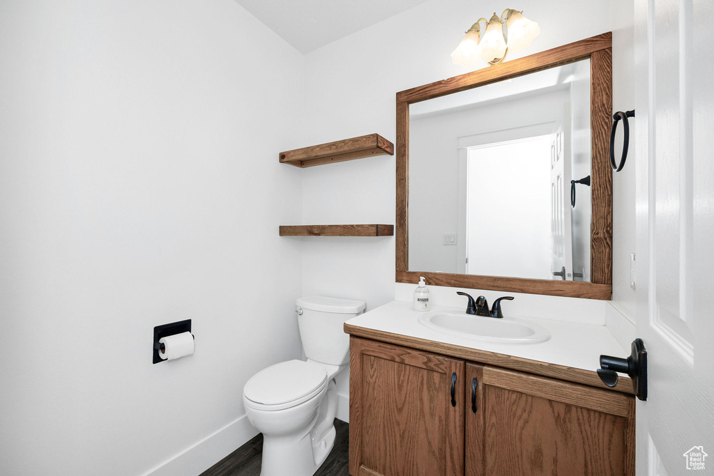 Half bath with toilet, baseboards, and vanity