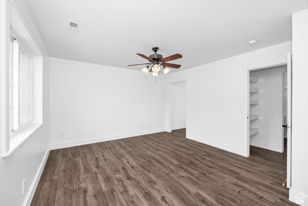 Unfurnished bedroom with dark wood-style floors, visible vents, ceiling fan, and baseboards