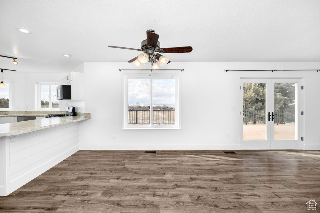 Unfurnished living room featuring french doors, baseboards, and wood finished floors