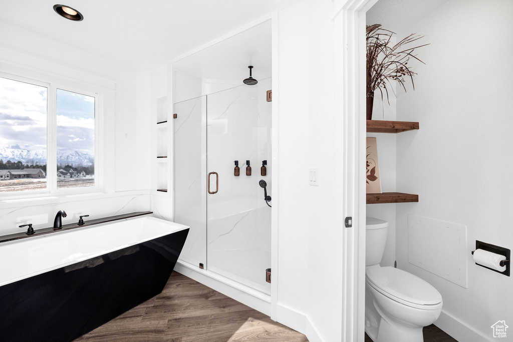 Full bath featuring toilet, a shower stall, and wood finished floors