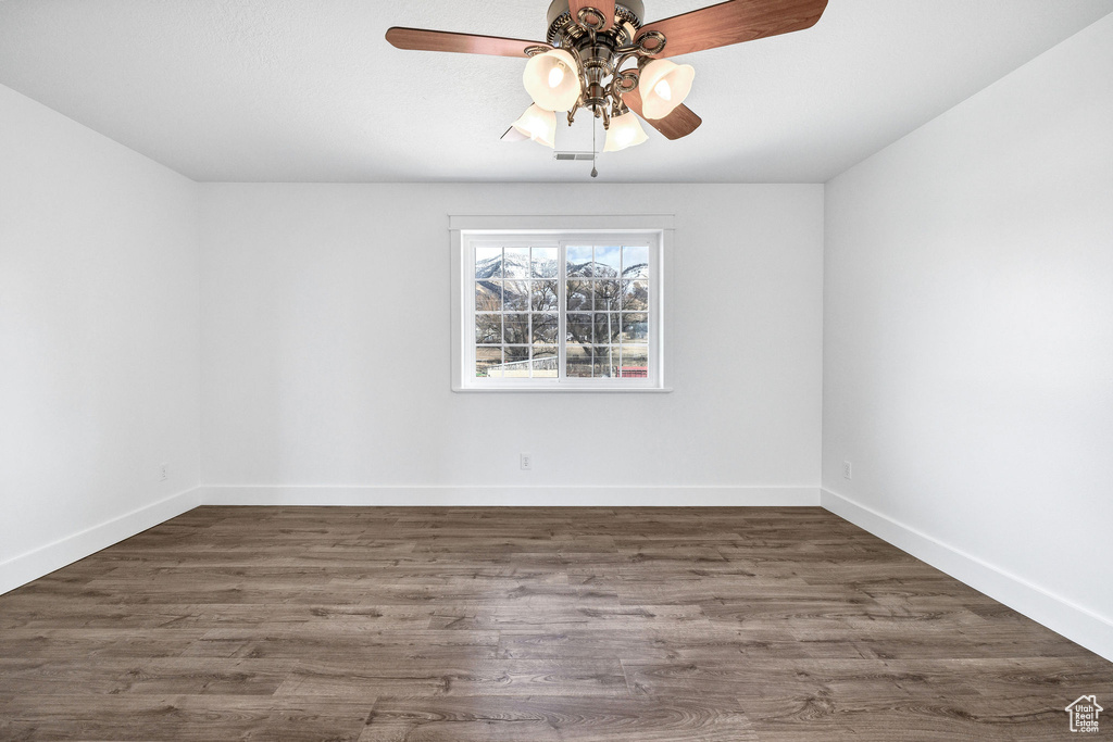 Spare room featuring a ceiling fan, baseboards, and wood finished floors
