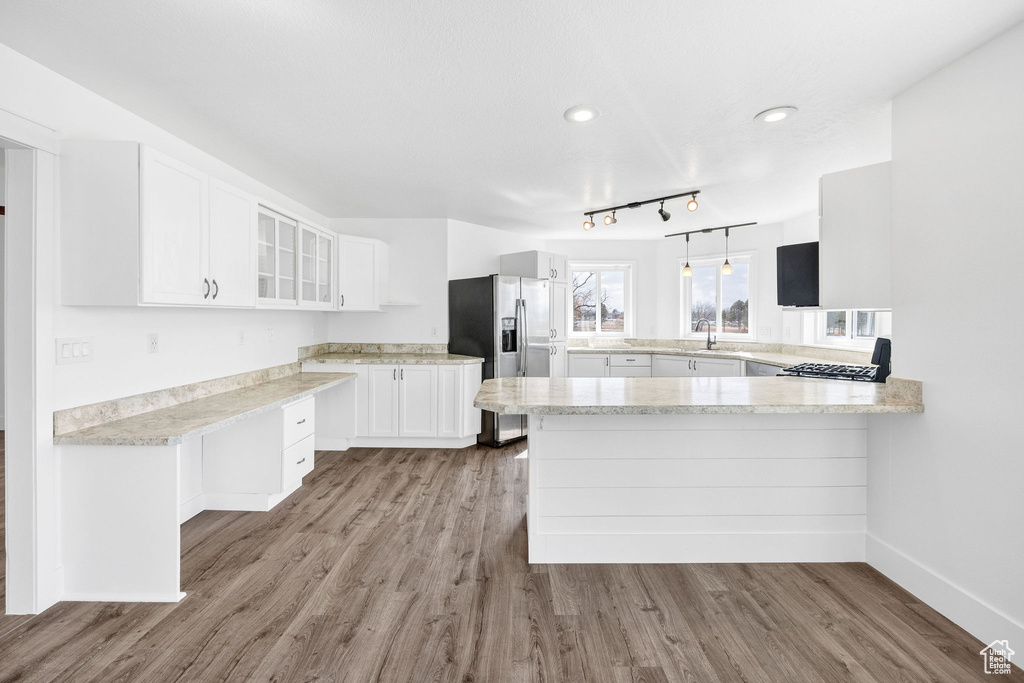 Kitchen with glass insert cabinets, white cabinets, wood finished floors, a peninsula, and stainless steel fridge with ice dispenser
