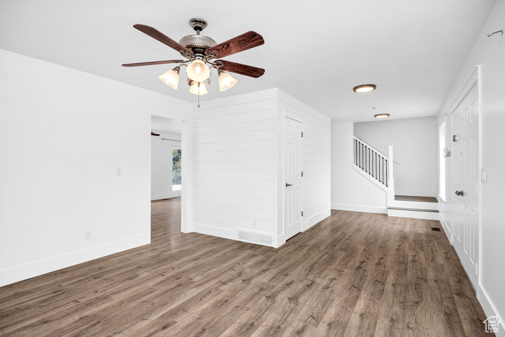 Unfurnished room with wood finished floors, visible vents, baseboards, and stairs