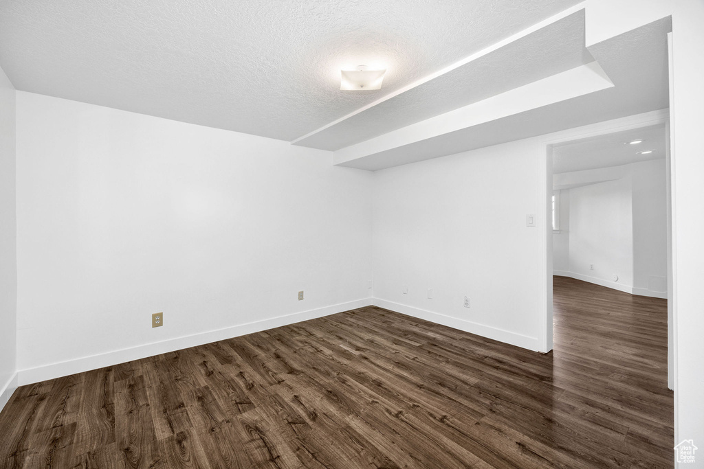 Unfurnished room with dark wood-style floors, a textured ceiling, and baseboards