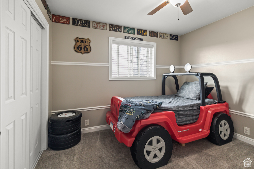 Carpeted bedroom with a ceiling fan, baseboards, and a closet